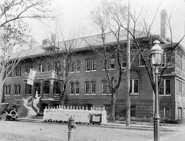 1917: Abbott Hospital staff (primarily student nurses) display banner honoring graduates who served in World War I.