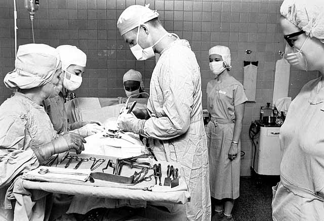 Dr. Frederick Drill and nurses operate on a patient  - January 1965